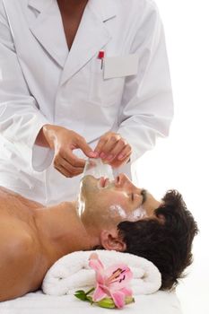 A salon worker removes a facial peel from a male patron