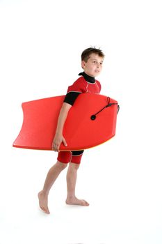 A boy carrying a bodyboard dressed in wetsuit ready for some summer fun.