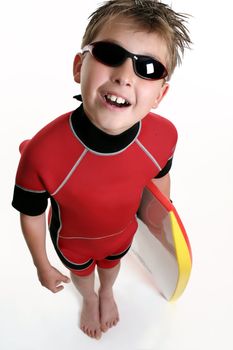 A child dressed in wetsuit and holding a board, is ready for the beach, 