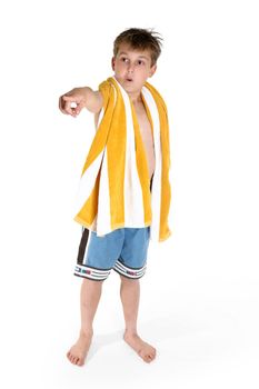 A young curious boy dressed in board shorts and beach towel around shoulders points his finger with a wide eyes expression of awe or wonder.