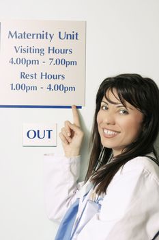 A nurse pointing to the hospital visiting hours sign