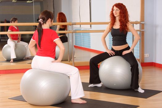 The pregnant woman with the instructor is engaged in gymnastics in a sports hall
