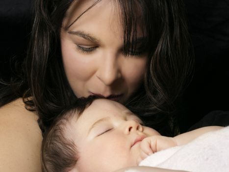 Mother kissing sleepy baby -- soft focus