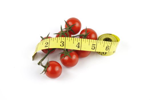 Small red ripe tomatoes on the vine with yellow tape streamer on a reflective white background