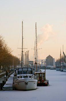 Frozen harbour with ships on cold day in winter  evening light