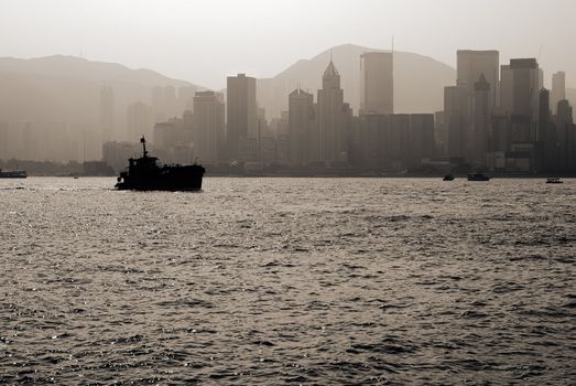 City skyline with silhouette of boat on the ocean in Hong Kong.