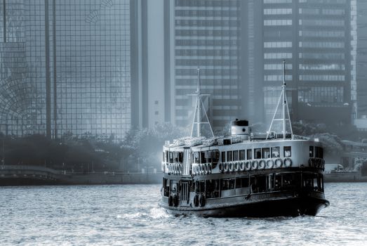 Barge on port in Hong Kong with tall buildings.