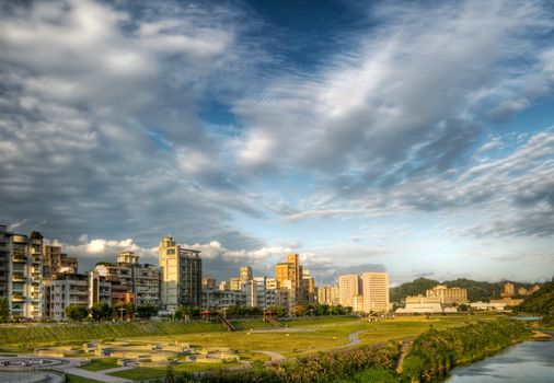 Cityscape of house with park and river under dramatic sky in Taipei, Taiwan.