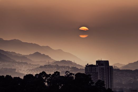 Landscape of city sunset with mountains and hills and buildings silhouette.