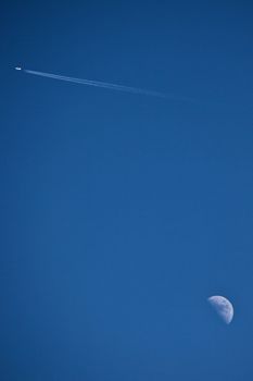 Moon and an aeroplane with a blue sky