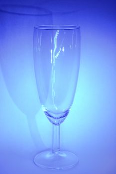 Single glass from delicate glassware on the blue background. 