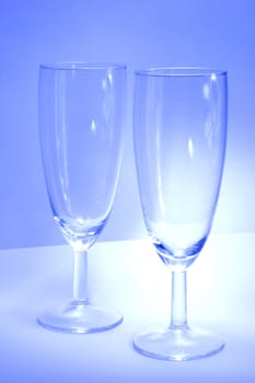 Two glasses from delicate glassware on the blue background. 
