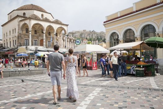 ATHENS, GREECE - MAY 24, 2011: Greece on the verge of bankruptcy. Tourism is a sector of hope for Greek economy. Athenians and tourists in touristic Monastiraki Square with market stalls, underground station, Tzistarakis Mosque and the Acropolis in the background.