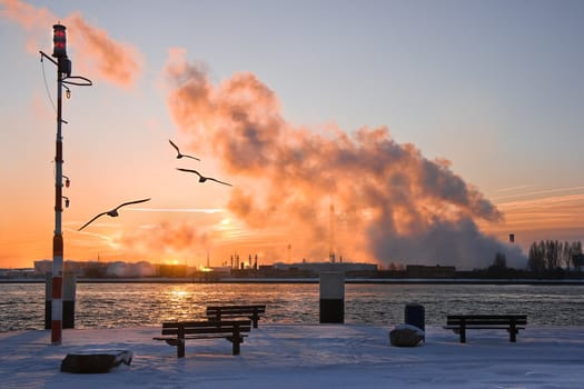 Industrial view with snow and pollution in winter at sunrise