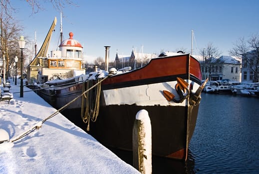 Sunny harbour with iron ship in winter snow - horizontal image