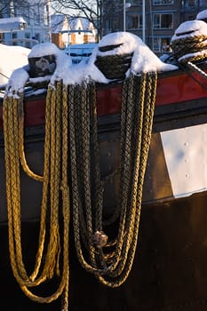 Ropes on ship in morning sun covered with snow - vertical image