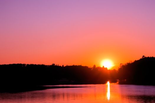 Sunset over lake. Setting sun on the cloudless sky