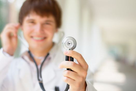Close-up portrait of a smiling young doctor holding a stethoscope