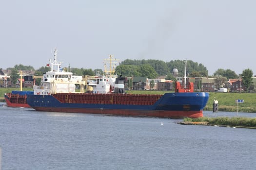 Middle size ship transporting containers over a canal