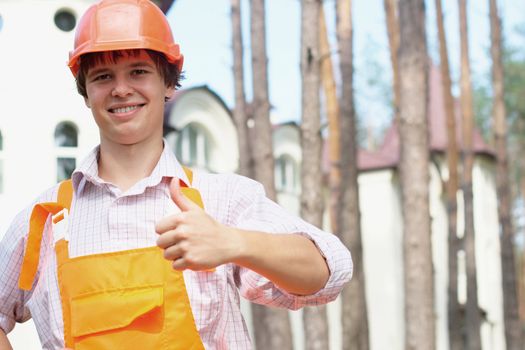 Close-up portrait of a smiling young worker in an orange hardhat outdoors