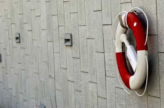 a red and white lifebuoy hanging on a stone wall
