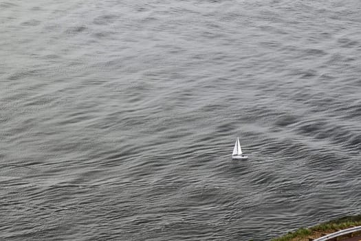 Small white sailboat on grey water
