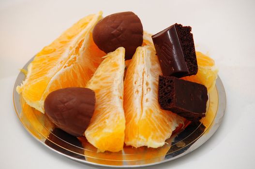 Slices of orange and chocolate candy on chrome plate.