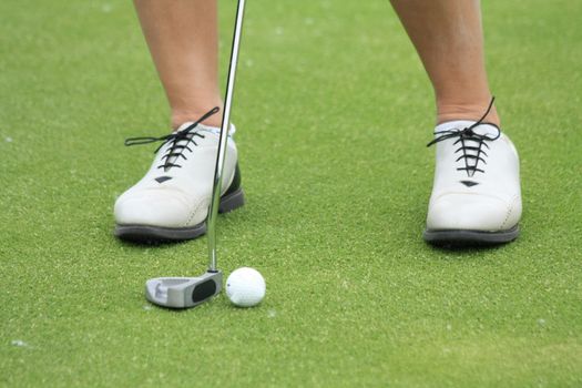 A woman practising golf on the chipping green