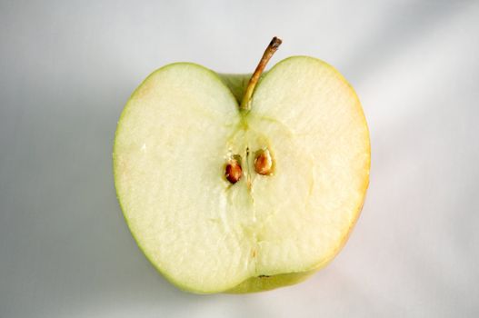 Half a green apple on a white surface.