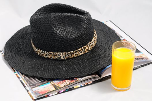 
Women's hat from the sun, a book and a glass of juice.

