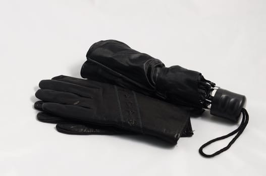 Black women’s gloves and umbrella on a white background .