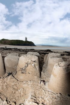childrens sandcastles on a beach in ireland with cliffs and real castle in background