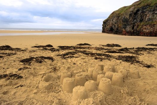 childrens sandcastles on a beach in ireland with cliffs in background