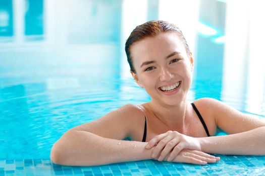 Close-up portrait of a smiling young beautiful girl at the swimming pool