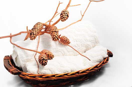 A basket of bath towels and bronze spruce cones.