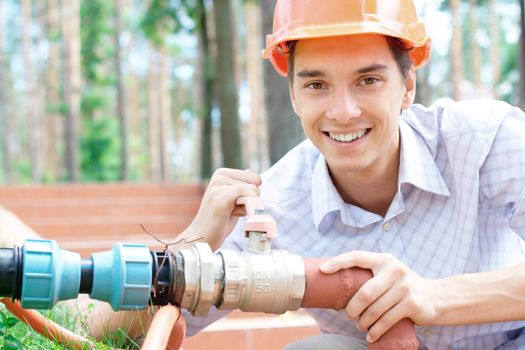 Close-up portrait of a smiling young worker repairing a pipe