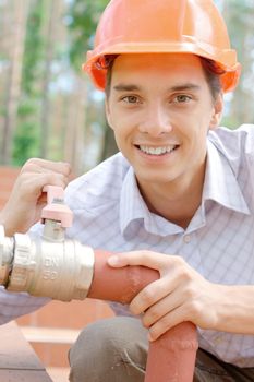 Close-up portrait of a smiling young worker repairing a pipe