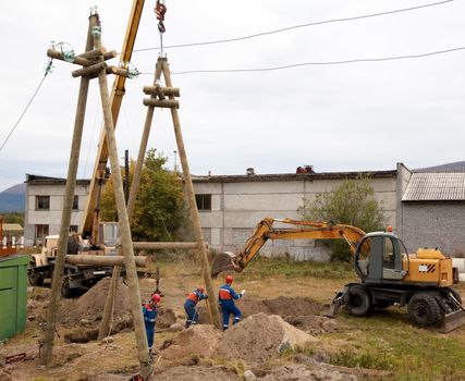 Installation support power lines with crane and excavator