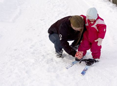 Mother teaching small child cross country skiing