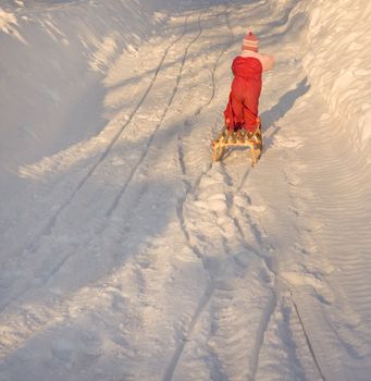 Child pulling a sleigh up a hill.