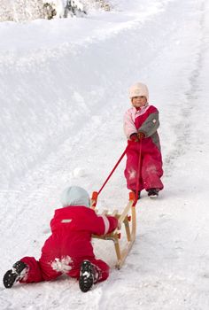 Children cooperating in getting a sleigh up a long hill. 