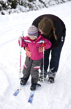 Mother teaching small child cross country skiing