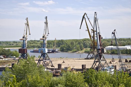 Cargo terminal for ships and barges on the river bank. Industrial landscape.