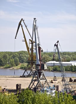 Cargo terminal for ships and barges on the river bank. Industrial landscape.