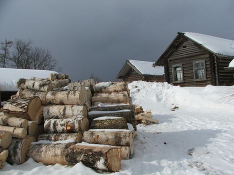 Winter. The entire village is covered with snow. Birch logs.