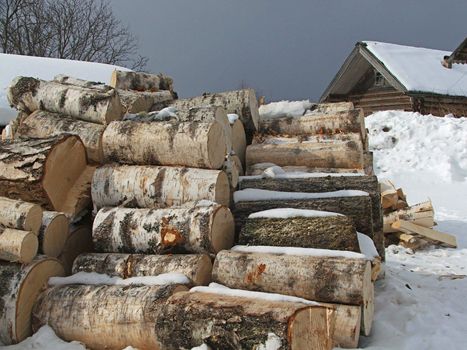 Winter. The entire village is covered with snow. Birch logs.