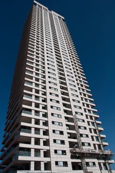 Exterior of modern high rise office building with glass windows and blue sky background.