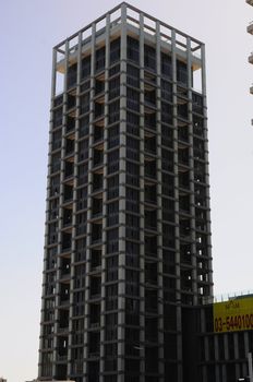 Exterior of modern high rise office building with glass windows and blue sky background.