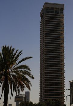 Exterior of modern high rise office building with glass windows and blue sky background.