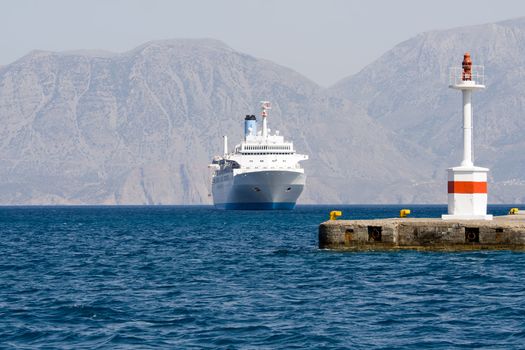 Tourist white cruise sea liner sails to lightship in rocky bay on the islands background